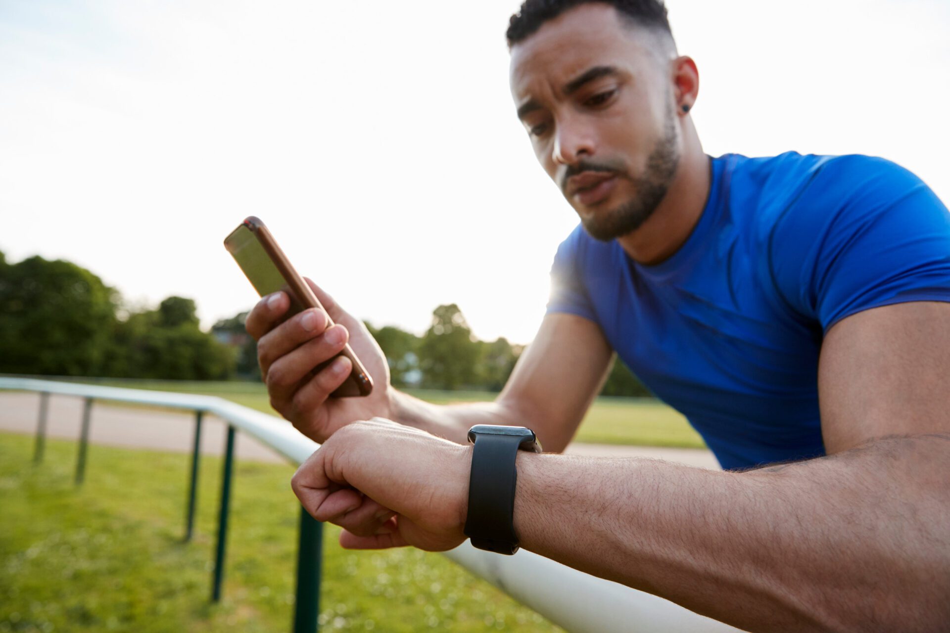 Male athlete using fitness app on smartphone and smartwatch